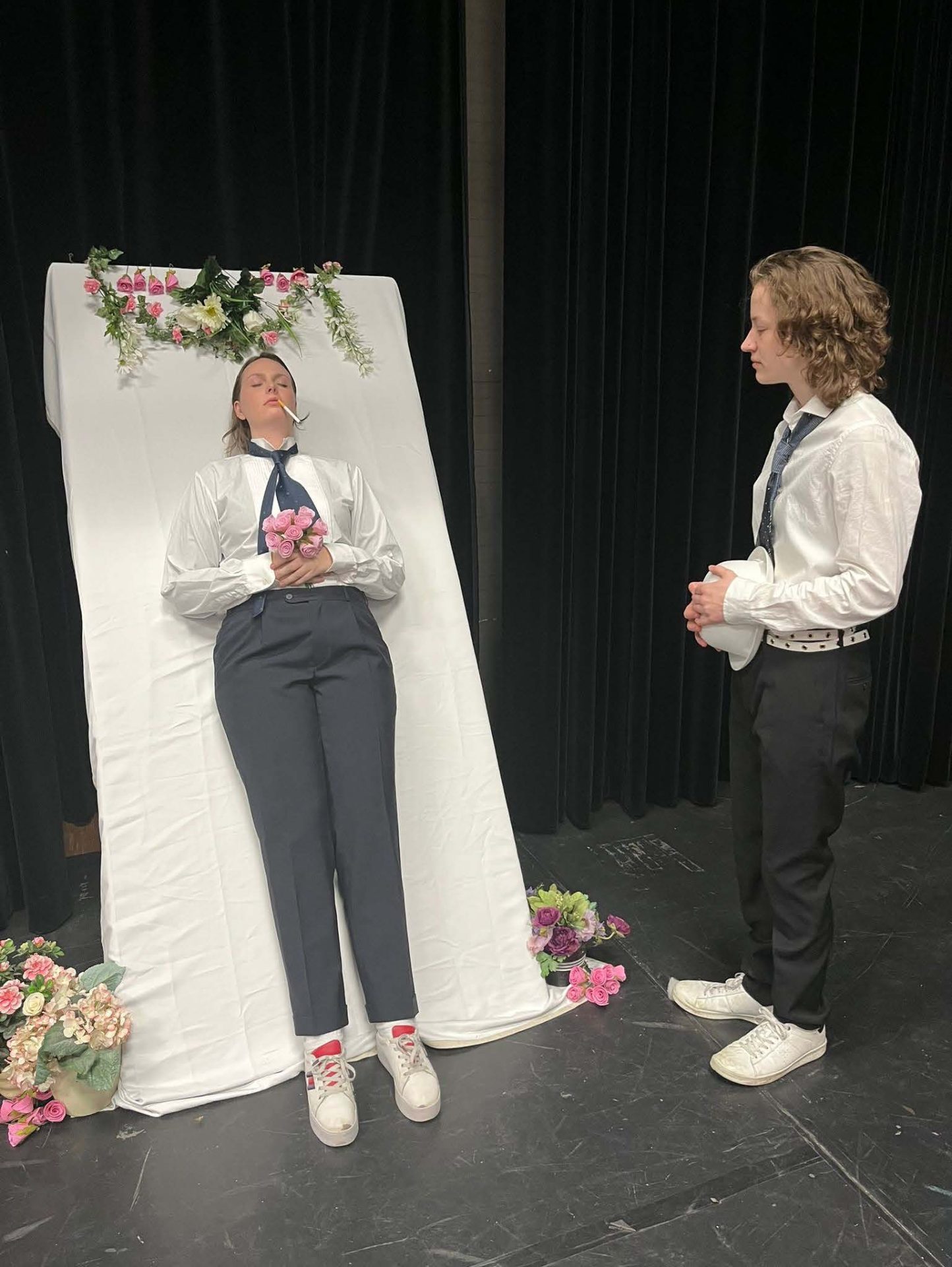 foto van twee personen in zwart witte kleding voor een gordijn en met bloemen