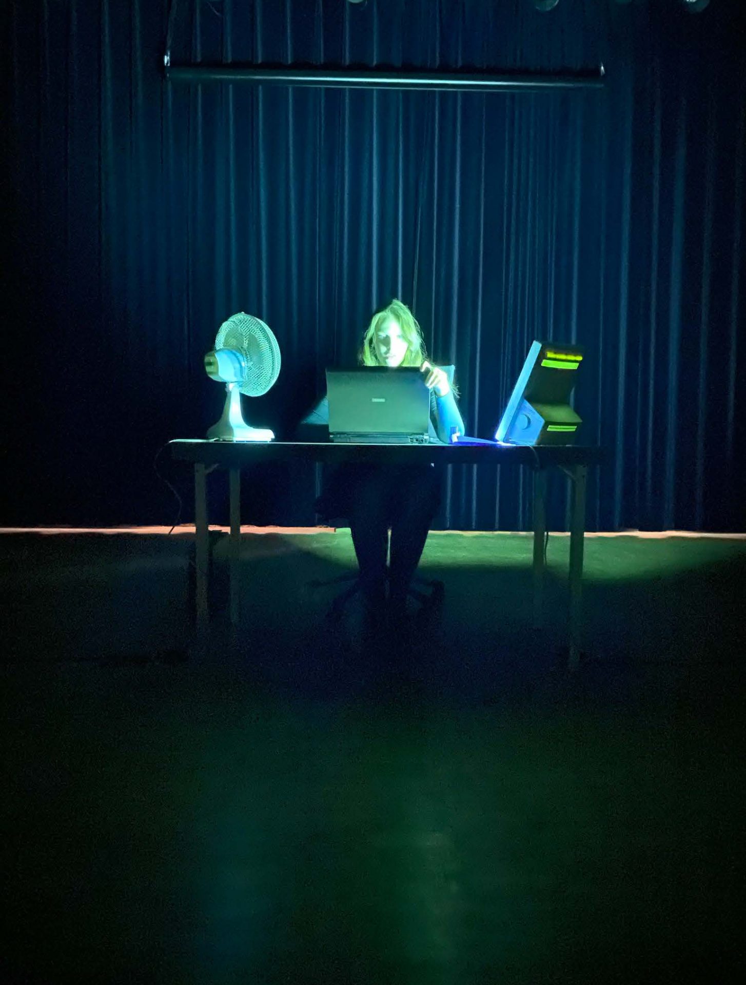 foto van een persoon achter een bureau met een laptop en een ventilator